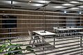 Die grauen Stühle sind um einen weißen langen Tisch ausgerichtet. Der Raum ist minimalistisch eingerichtet.
