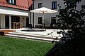 Ein Sonnenschirm und Liegestühle sind auf einer hellen Terrasse platziert.