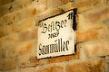Die Steinwand ist mit einem Schild "Sammüller" geschmückt.