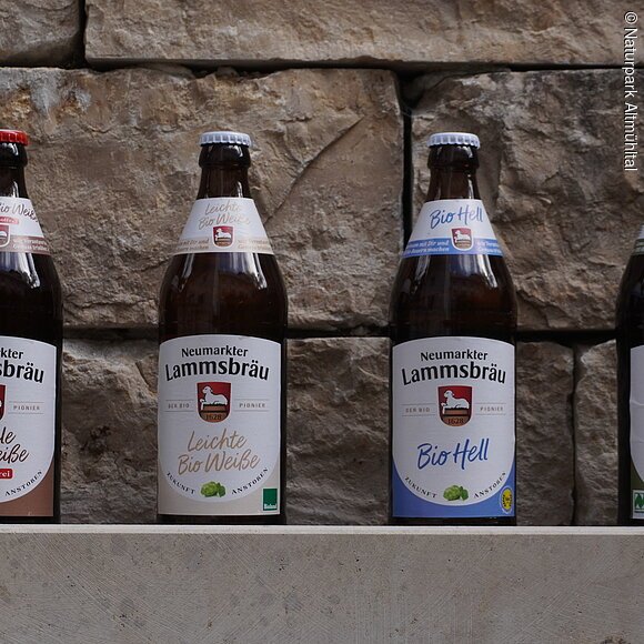 Bier Brauerei Neumarkter lammsbräu Vier Flaschen Neumarkter Lammsbräu Bier stehen vor einer Steinwand.