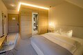 Ein Einzelzimmer im Berghotel Sammüller Hotelzimmer mit Doppelbett, Schreibtisch, Stuhl, Holzwand und offenem Bad mit Toilette und Handtüchern