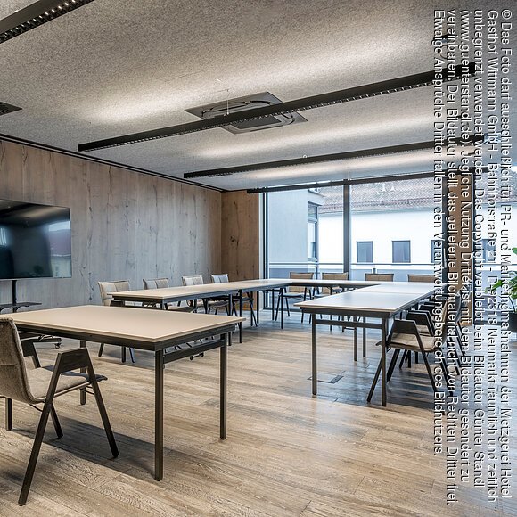 Großer Tagungsraum im Wittmanns Neumarkt Fensterseite Moderner Besprechungsraum mit rechteckigen Tischen, Stühlen, großem Bildschirm und Fensterfront.